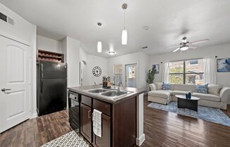 A kitchen with a black refrigerator and a brown island.