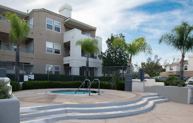 A swimming pool in front of a two-story apartment building.