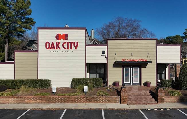The front of the Oak City Apartments building is shown with a clear blue sky in the background.