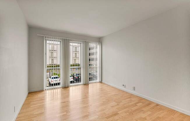 A room with wooden floors and white walls with a window and a door.