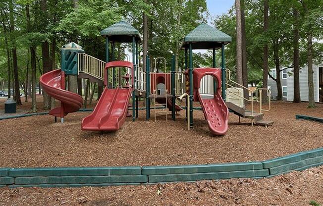 a playground with two slides and two swings at Trails at Short Pump Apartments, Richmond