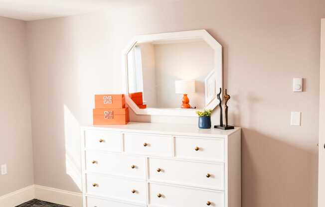 a dresser with a mirror on top of it in a bedroom