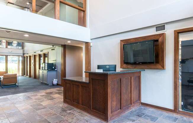 A reception area with a wooden desk and a television on the wall.