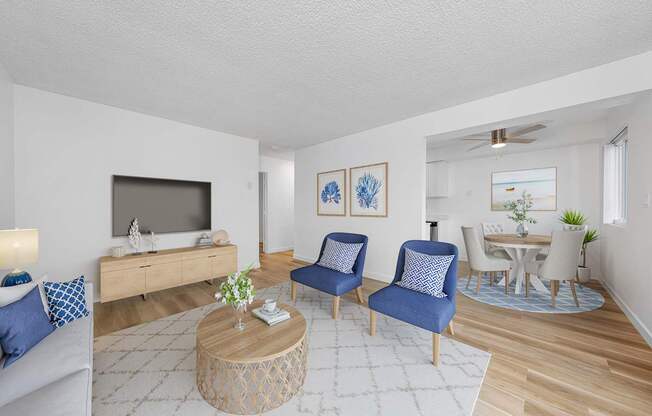 A living room with a television, two chairs, a coffee table, and a dining table.