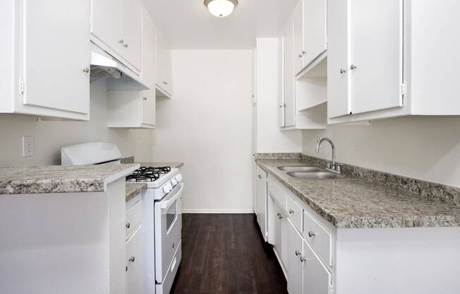 a kitchen with white appliances and granite counter tops and white cabinets