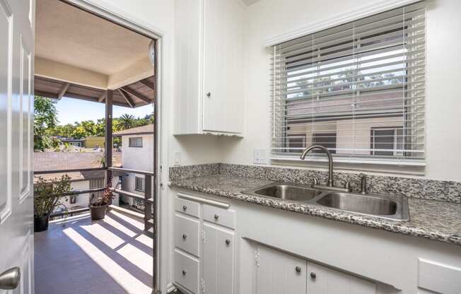 a kitchen with a sink and a window and a door to a balcony