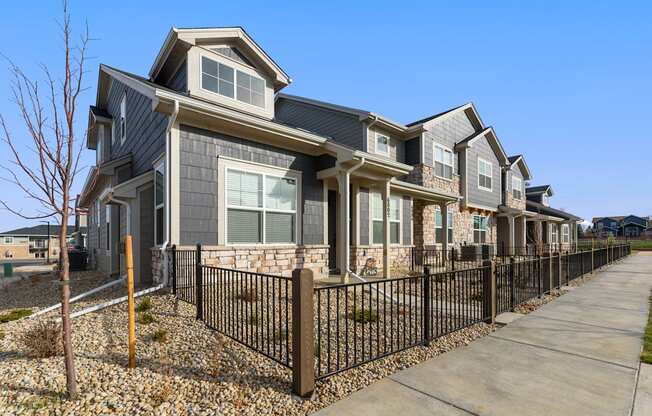 a row of houses with a sidewalk and a fence