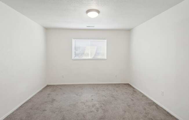 an empty room with carpet and a window