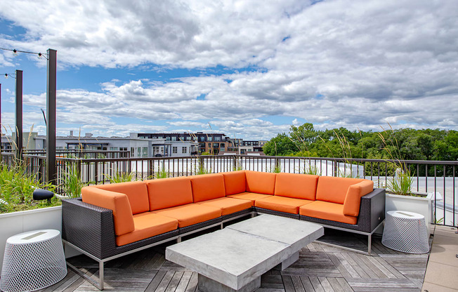 A patio with a grey table and an orange couch.