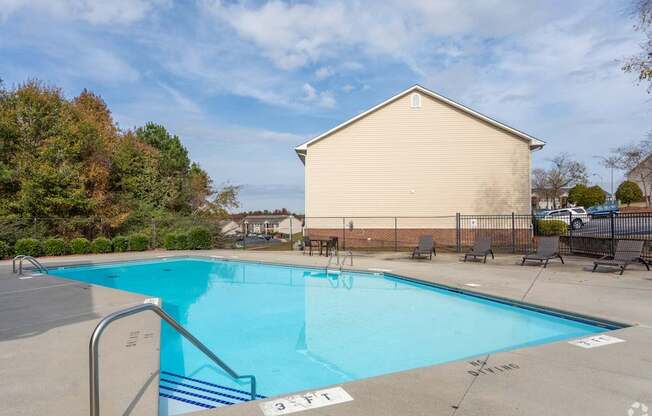 A swimming pool with a diving board and a building in the background.