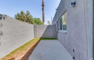 the backyard has a concrete walkway and a wall with a window