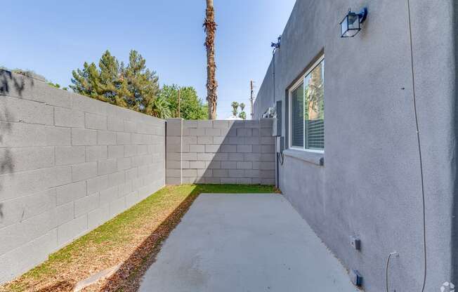 the backyard has a concrete walkway and a wall with a window