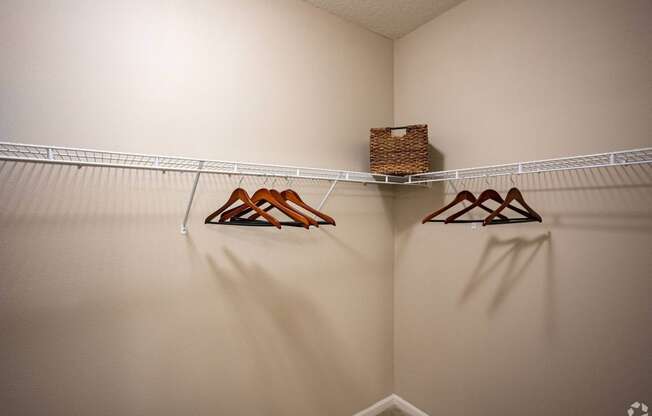 a walk in closet with hooks and a basket on the wall