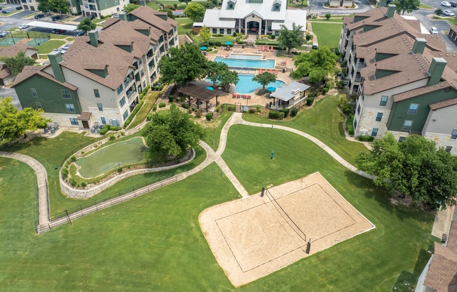 an aerial view of an apartment complex with a swimming pool and lawn
