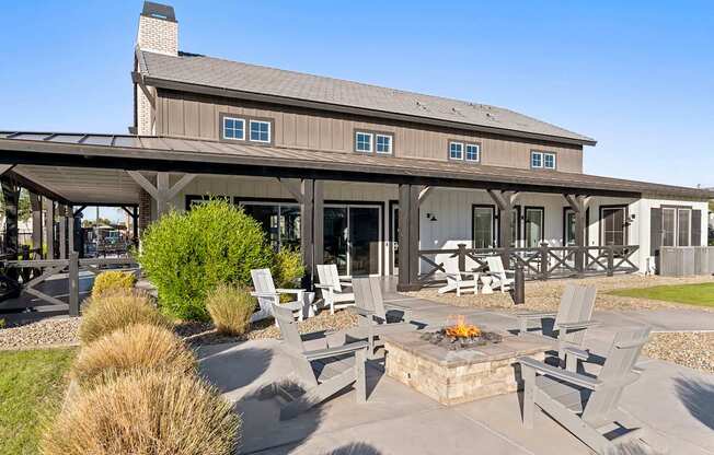 A patio with chairs and a fire pit in front of a house.