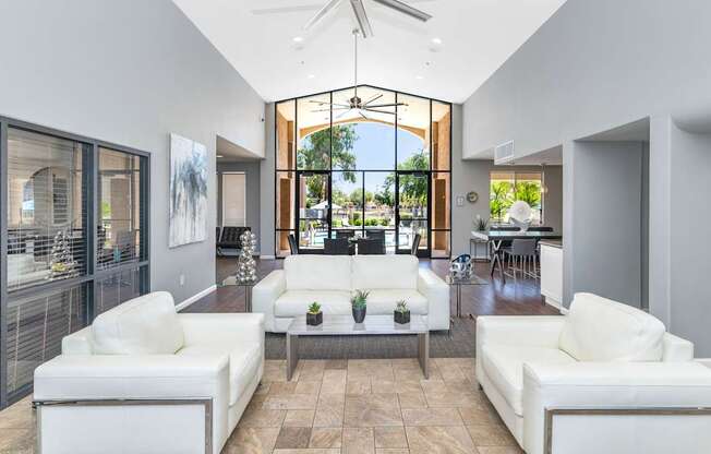 A modern living room with white furniture and a large window.