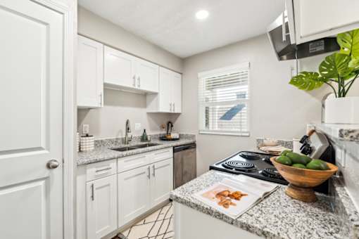 A kitchen with white cabinets and granite countertops.