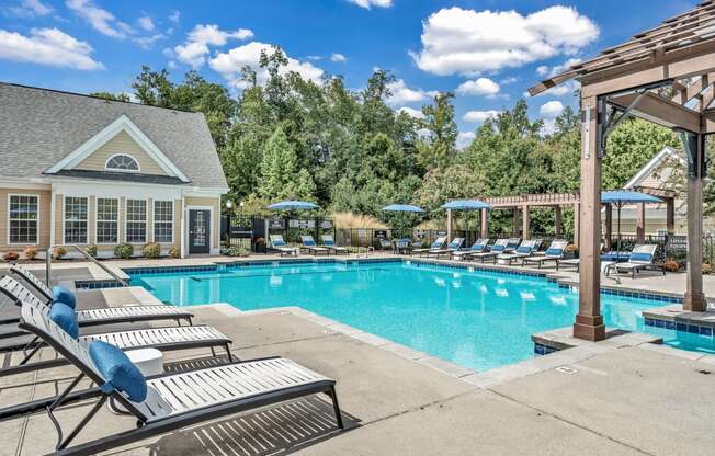 the resort style pool with lounge chairs and umbrellas