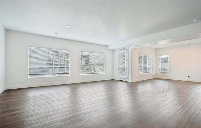A large empty room with wooden floors and windows.