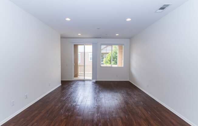 an empty living room with white walls and wood floors at The Vines at Riverpark, LLC, California, 93036