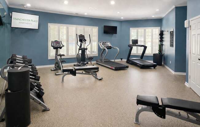 A gym with a variety of equipment including treadmills, weights, and exercise machines.