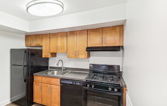 a kitchen with black appliances and wooden cabinets and a black refrigerator