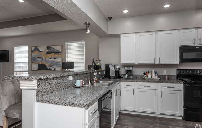 A kitchen with white cabinets and a granite countertop.