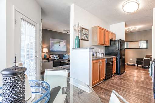 A kitchen with a black fridge and wooden cabinets.