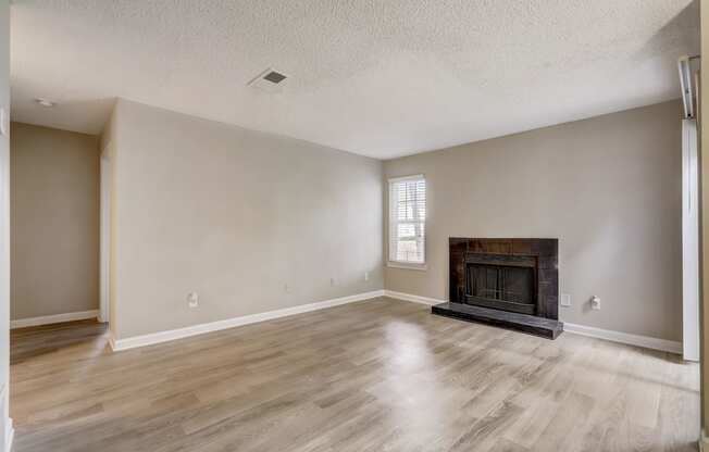 a spacious living room with pet-friendly hardwood floors and black fireplace and natural light at Veridian at Sandy Springs
