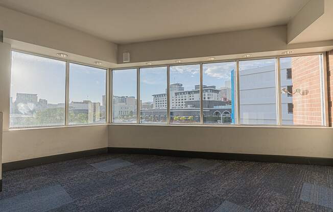 an empty living room with large windows and a city view