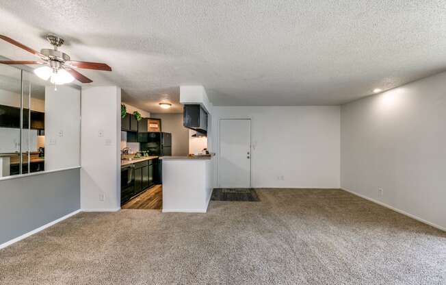 an empty living room and kitchen with a ceiling fan