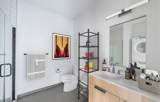 a bathroom with a toilet sink and a shower and a washing machine