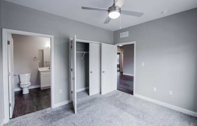 an empty bedroom with a ceiling fan and a bathroom