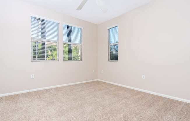 a bedroom with a ceiling fan and three windows