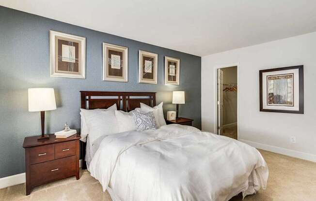 A bedroom with a large bed and a nightstand with a lamp.