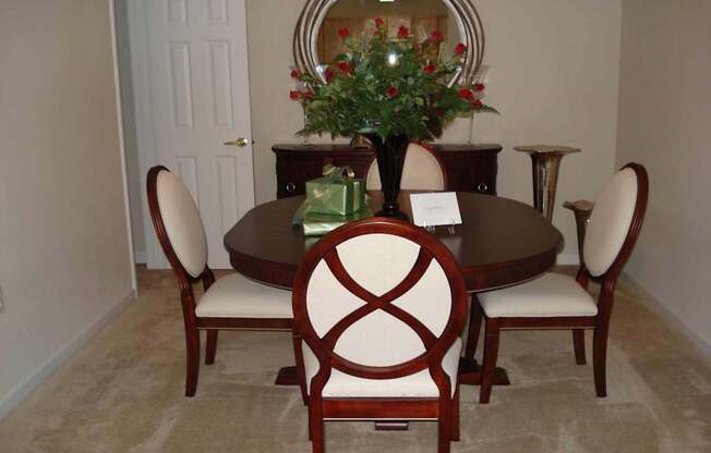 A brown table with a vase of flowers and chairs around it.