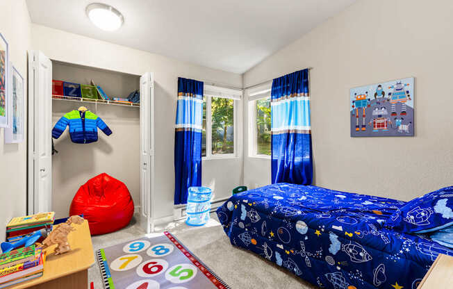 A child's bedroom with a blue bed and a numbered rug.