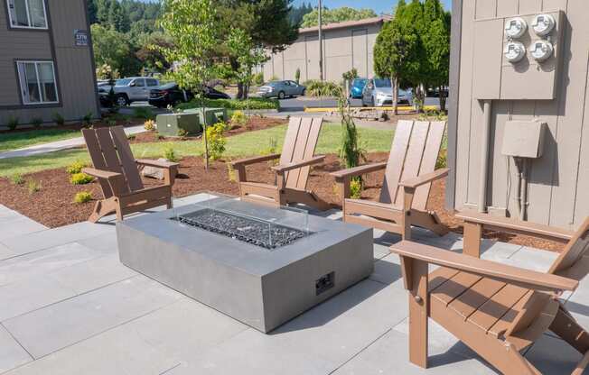 a firepit with two chairs around it and a parking lot in the background