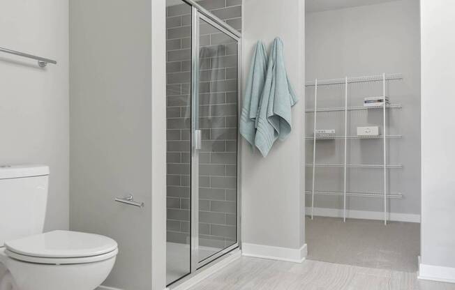 A bathroom with a toilet, a glass shower door, and a towel hanging on the door.