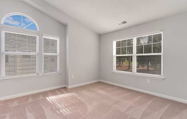 an empty living room with windows and carpeting