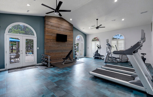 a home gym with two treadmills and a tv on the wall