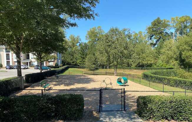 A park with a basketball court and a green sign with a white border.