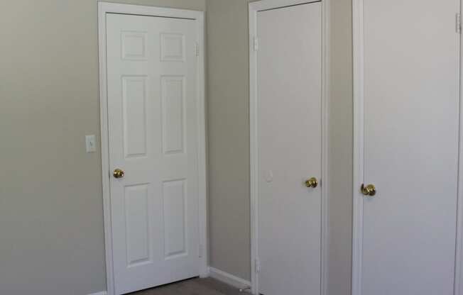 A room with a ceiling fan and three doors.