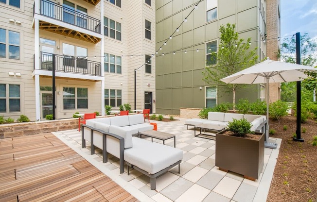 an outdoor patio with couches and chairs and an umbrella