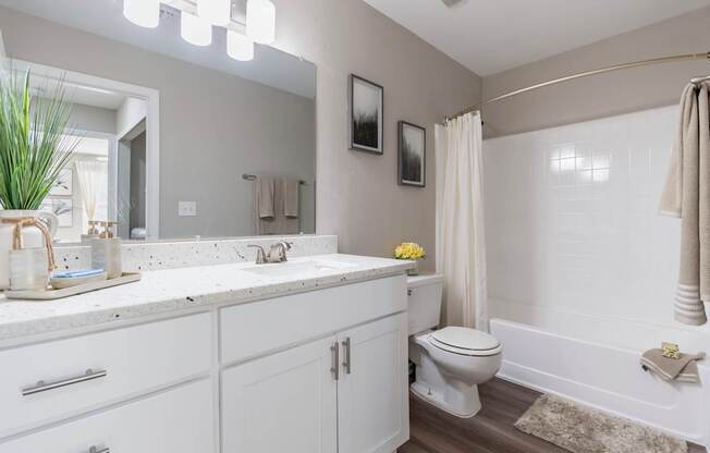 A white bathroom with a toilet, sink, and mirror.