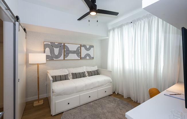 a bedroom with a white bed and a ceiling fan