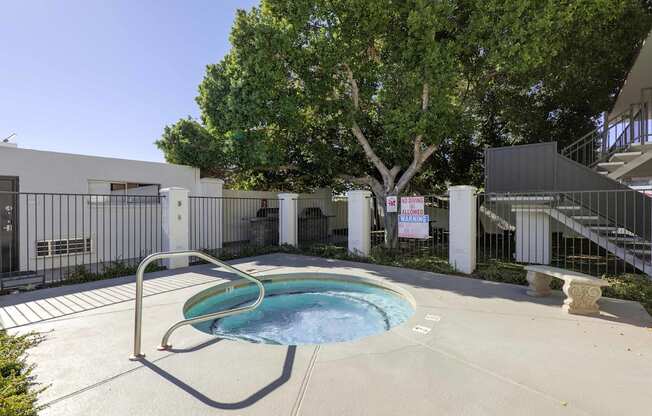 A pool surrounded by a fence and trees.