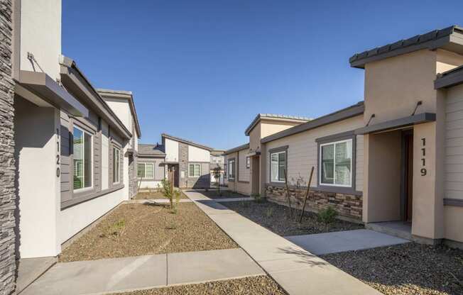 a pathway between two houses with a blue sky in the background at Grandstone at Sunrise, Peoria, AZ