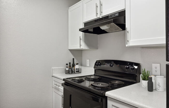 a kitchen with white cabinets and a black stove top oven