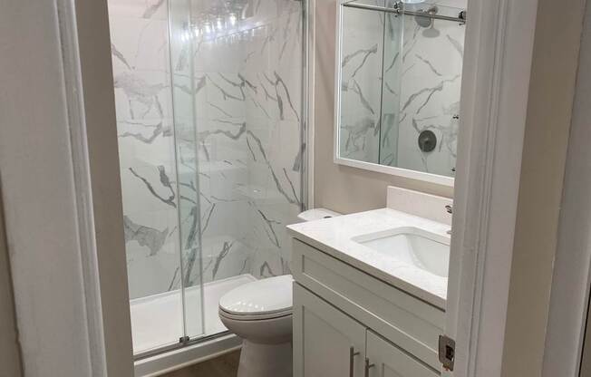 A white bathroom with a marble shower.